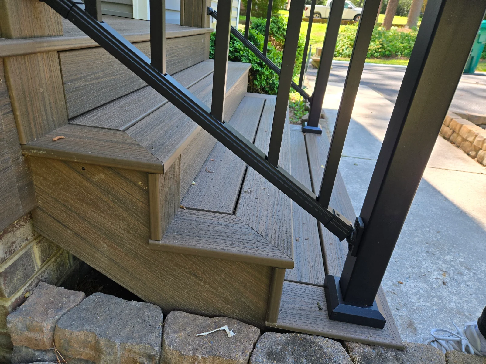 Brown composite deck stairs with black aluminum railing and newel post base plate
