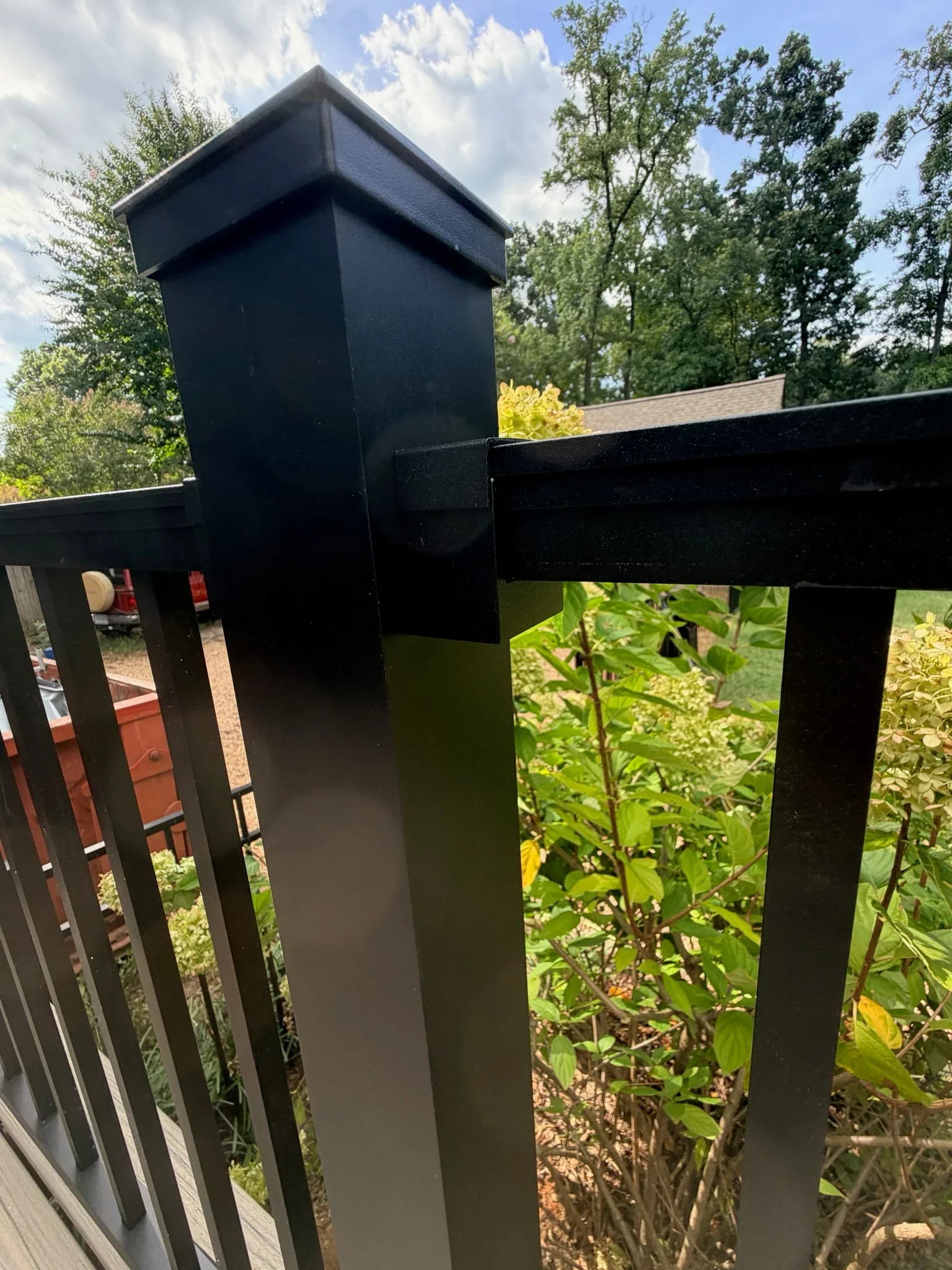 Black aluminum deck railing with square post cap, horizontal top rail bracket, and vertical square balusters