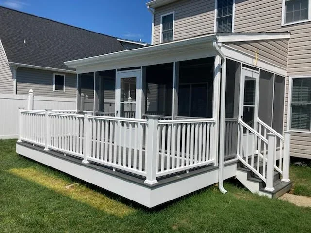 Screened porch with white vinyl railings, gray deck boards, and white-framed screen panels with a side staircase