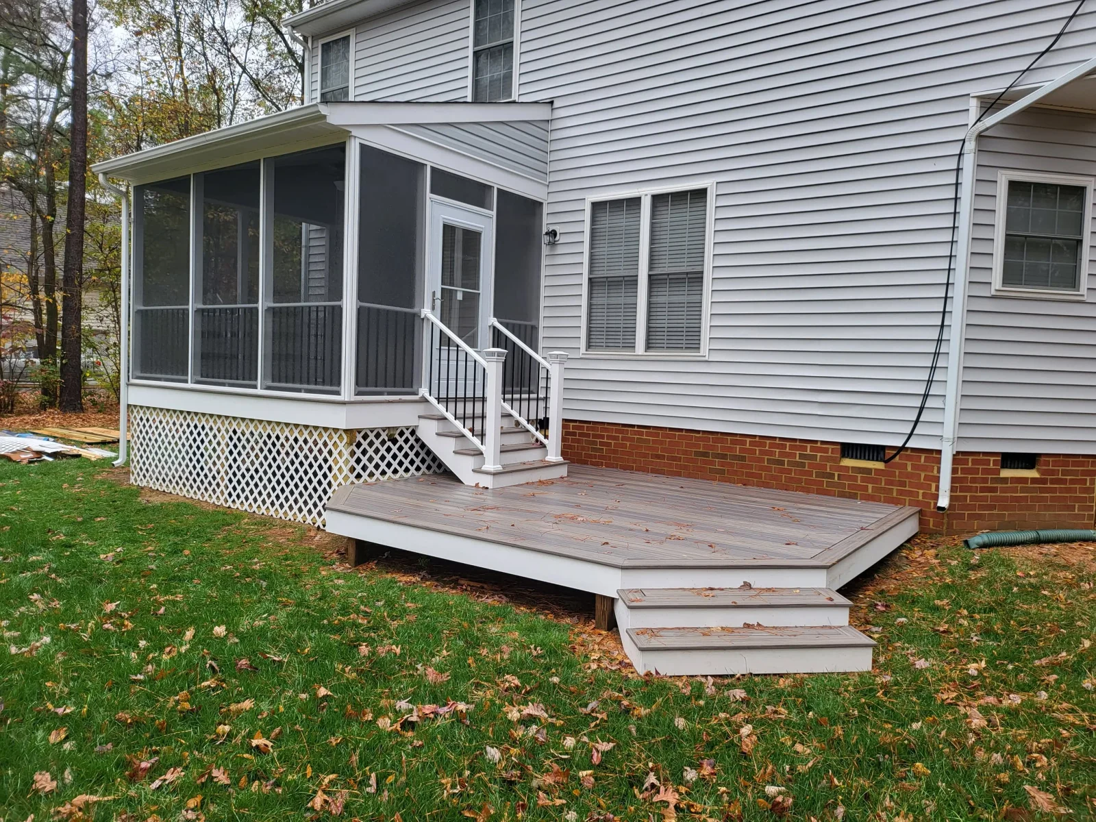Screened porch with white frame and composite gray deck with white railed stairs and lattice skirting