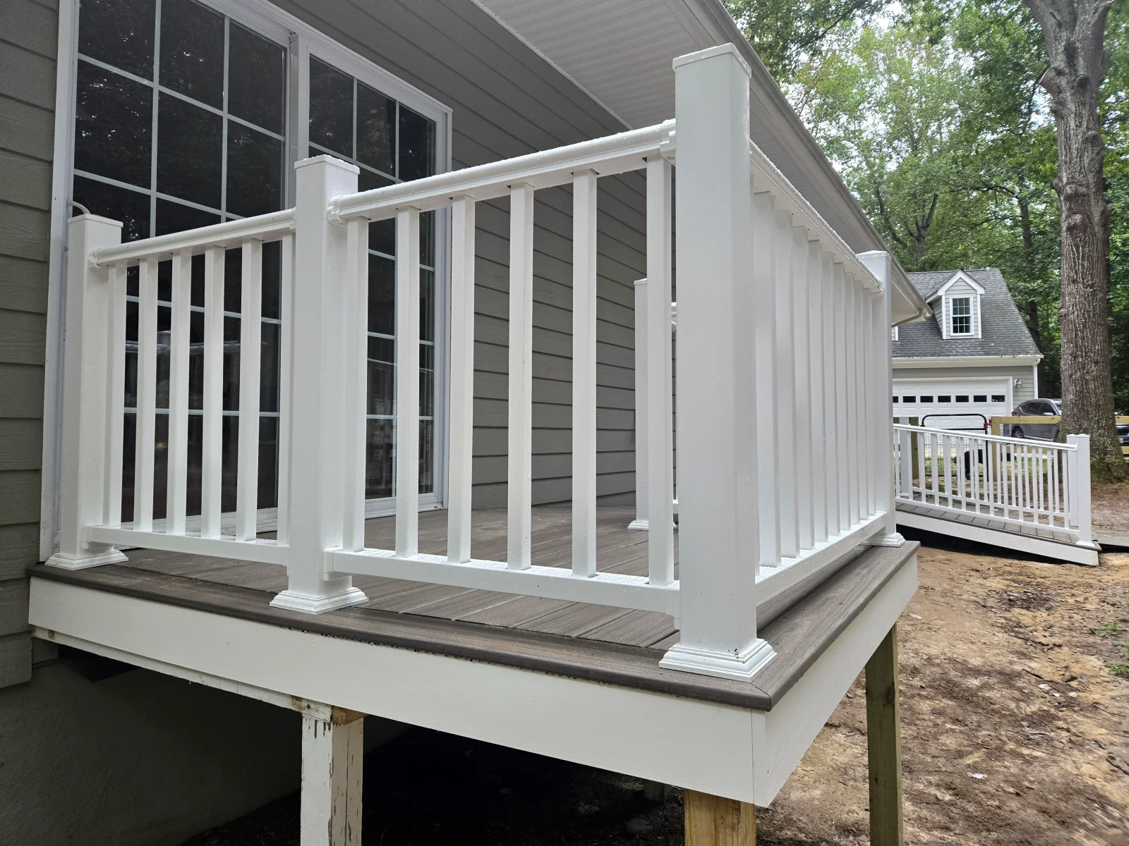 White railed elevated composite deck with gray-brown decking, square balusters, and matching white ramp railing